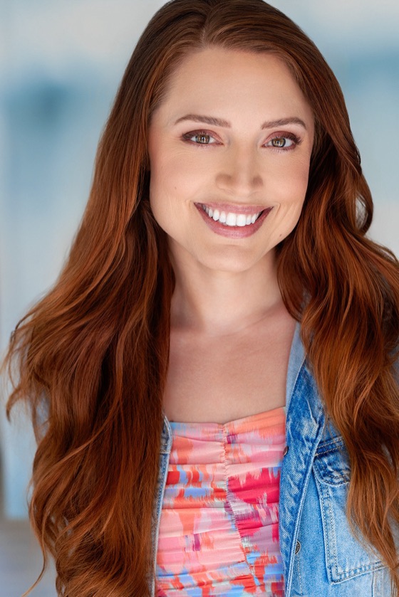 Headshot of Katelynn smiling in a denim jacket and coral patterned top