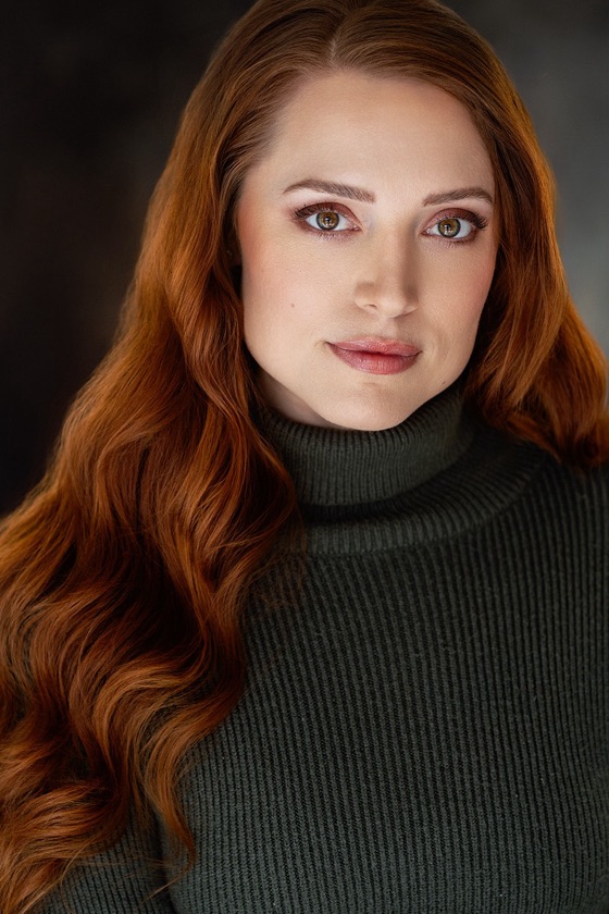 Headshot of Katelynn with a serious expression in an olive turtleneck