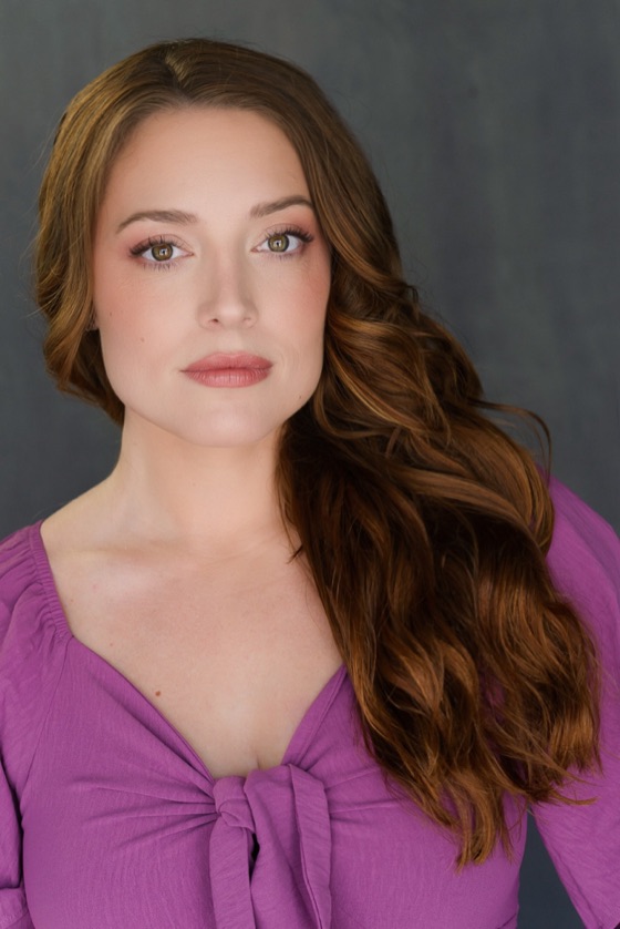 Headshot of Katelynn in a purple knotted top against a gray backdrop