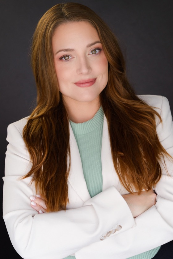 Headshot of Katelynn in a white blazer and mint sweater with arms crossed